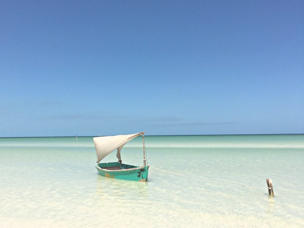 A boat in shallow water on the beach, tied to a short post.